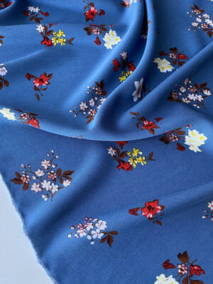 Віскоза твіл рідко розташовані букетики червоно-жовто-біли квітів на красивому димчато-синьому фоні