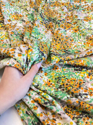 Віскозний льон з розсипом міленьких помаранчових квіточок та зелених листиків на світлому фоні