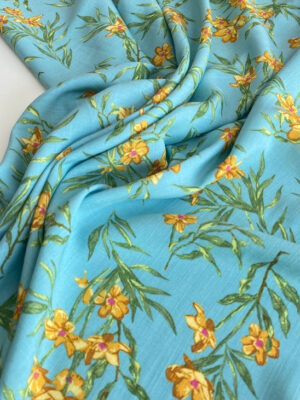 Віскозний льон ніжного бірюзовго кольору з жовто-помаранчовими квіточками і зеленим тонким листям