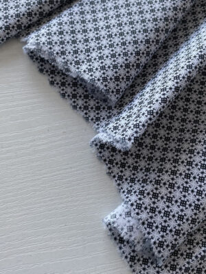 Стрейч-котон з міленькою мереживною графікою сірого кольору на білому